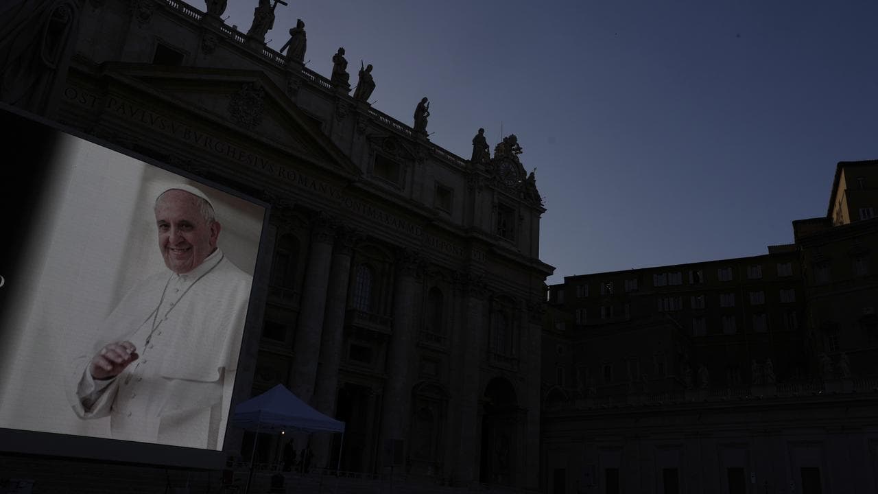 Pope Francis is projected on a screen next to St Peter's Basilica