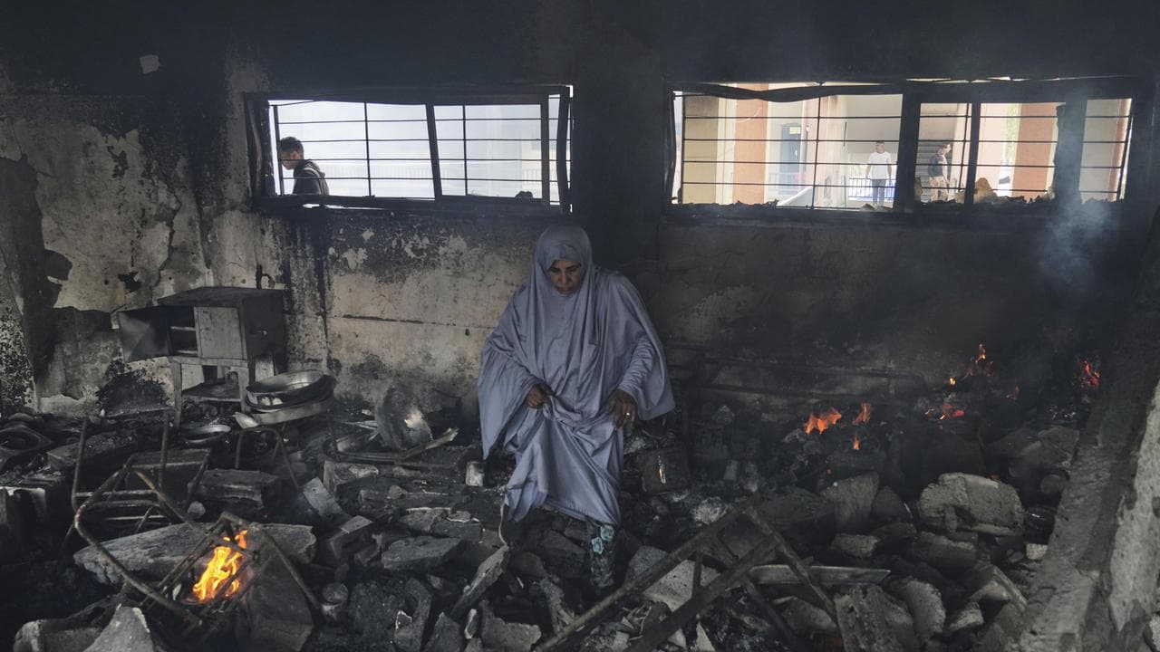 Pelstinian woman inspects damage after a strike on Yaffa School