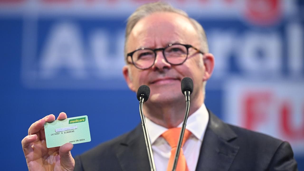 Anthony Albanese holds up a Medicare card during a campaign rally
