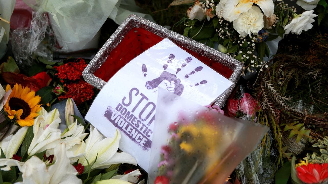 Sign among floral tributes reads Stop Domestic Violence