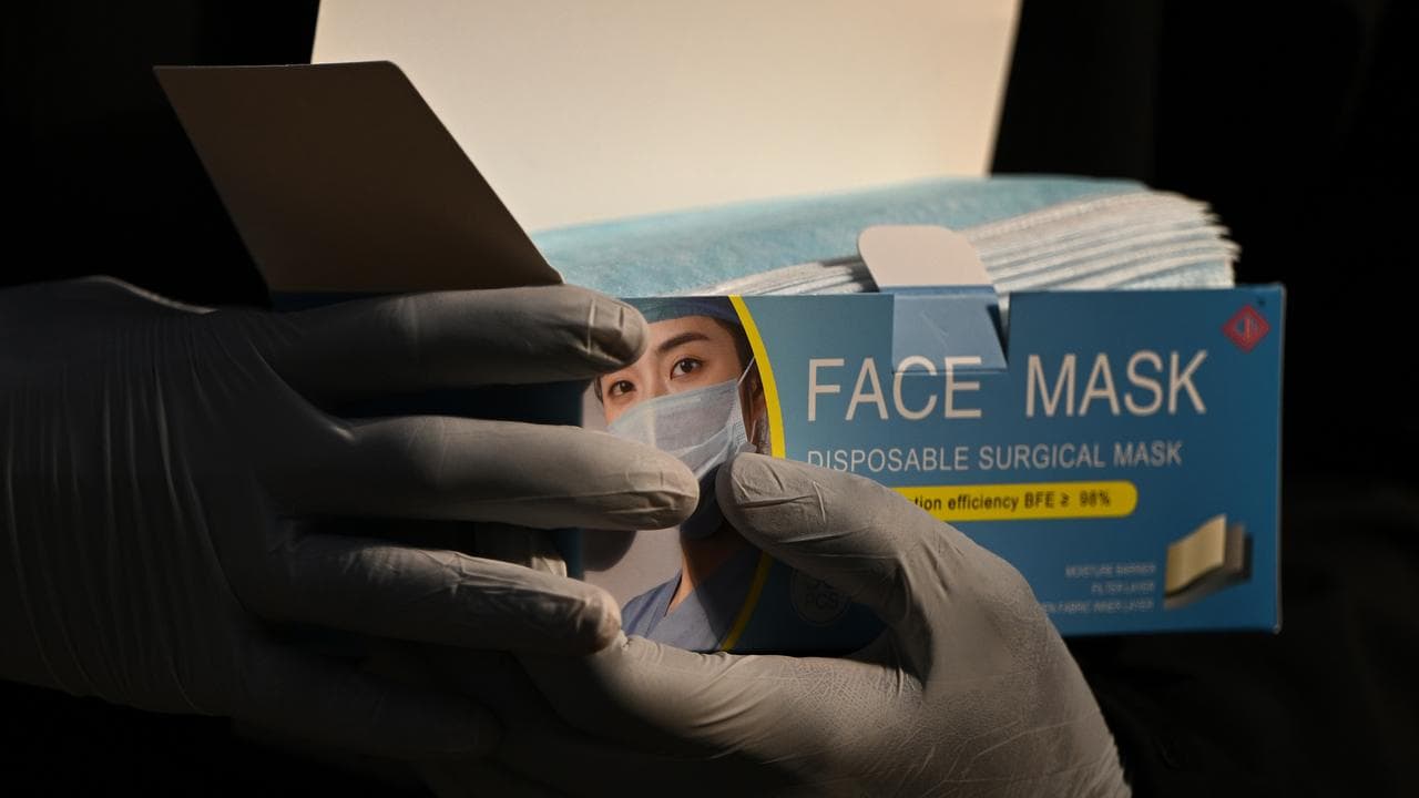 Workers hand out surgical masks , Melbourne, Monday, January 24, 2022
