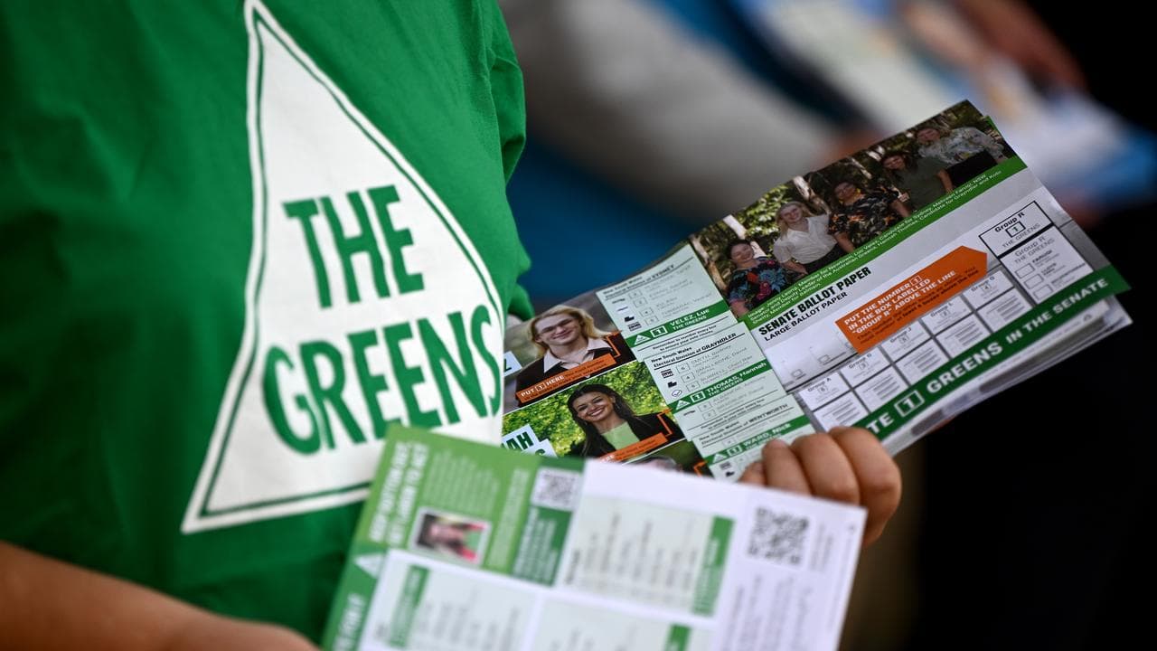 A person hands out Greens how to vote pamphlets.