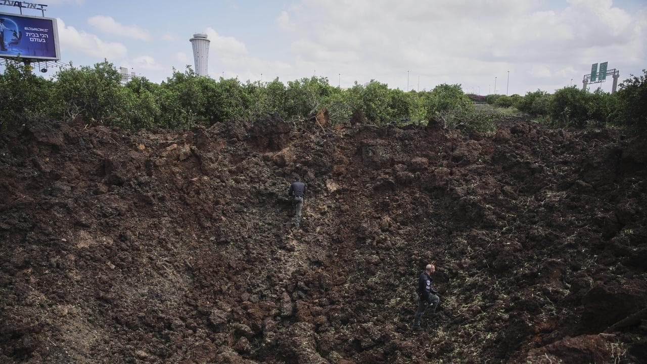 Israeli security forces inspect a crater