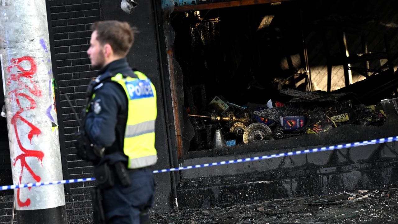 Police officer outside a tobacco shop destroyed by arson