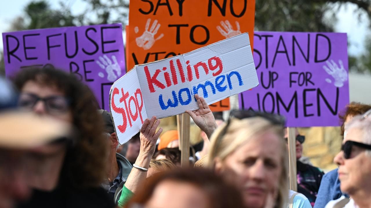People hold signs at a rally to end violence against women