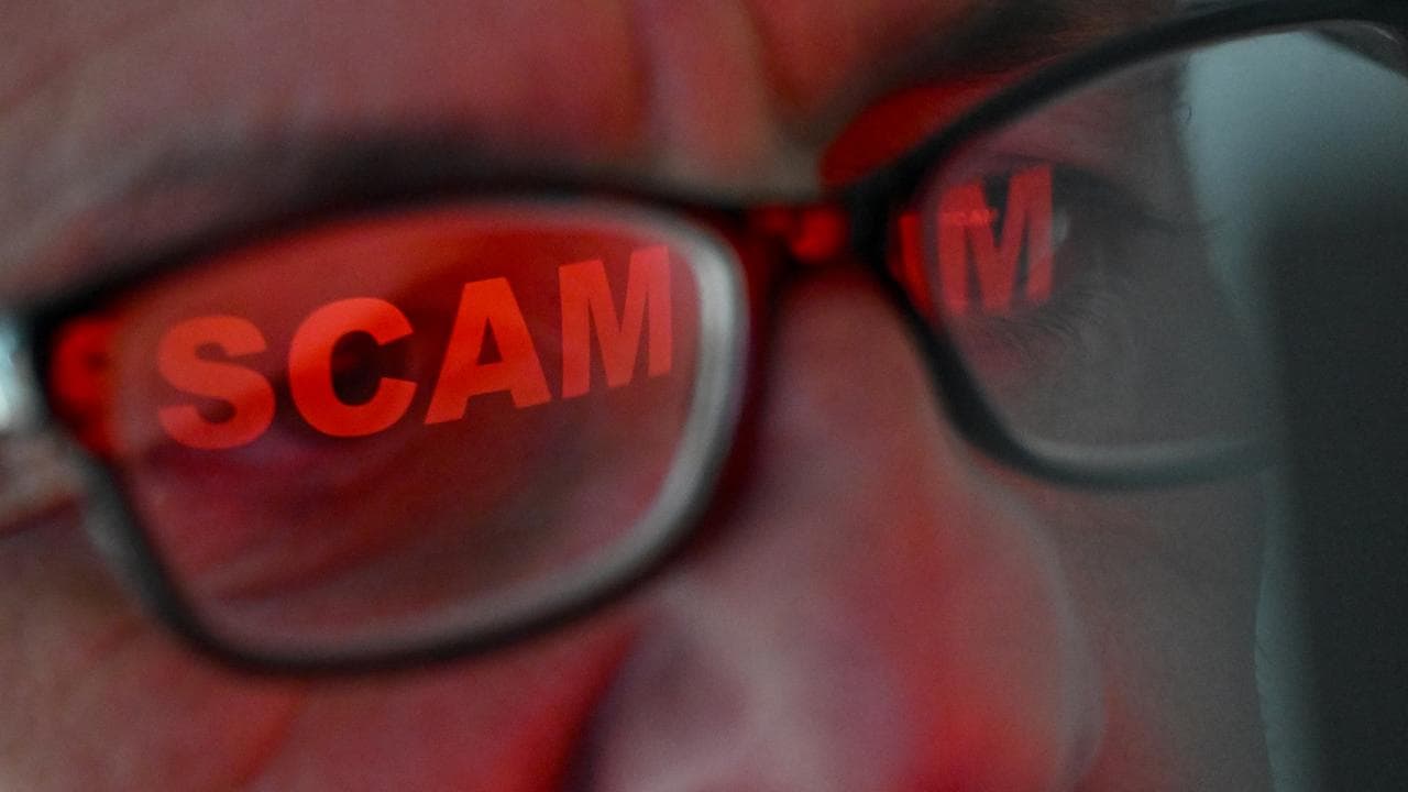 The word ‘scam’ is seen reflected in a person’s glasses (file image)