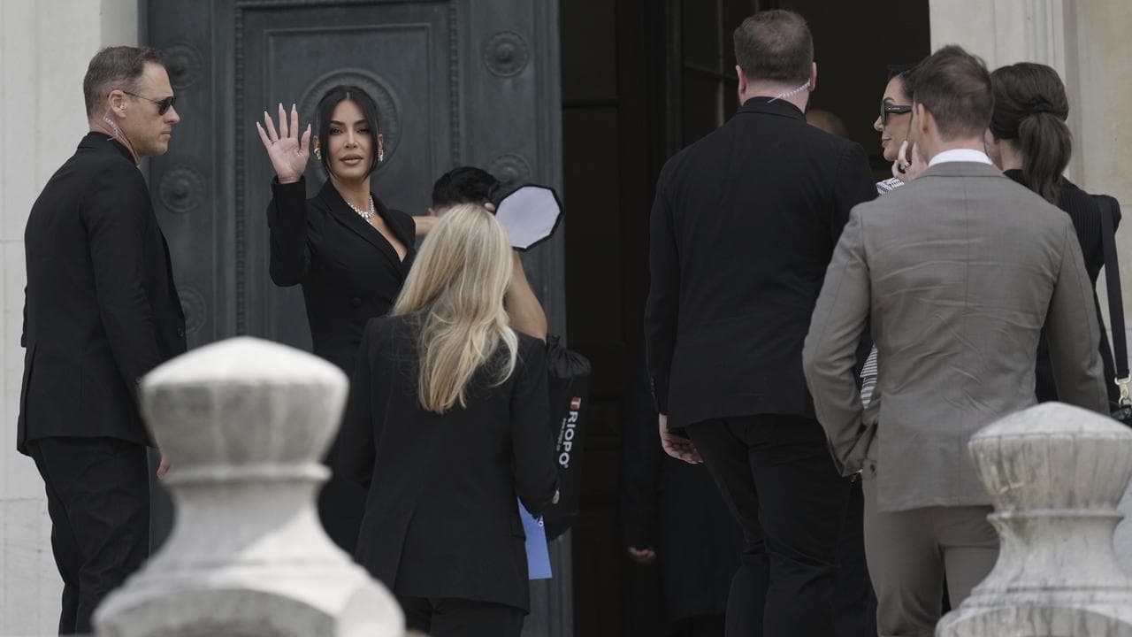 Kim Kardashian waves as she arrives to testify at a Paris court