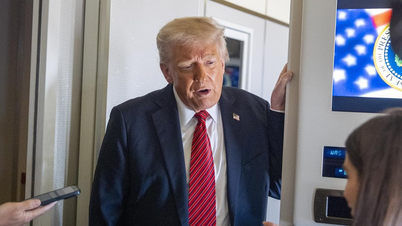 US President Donald Trump speaks to reporters aboard Air Force One