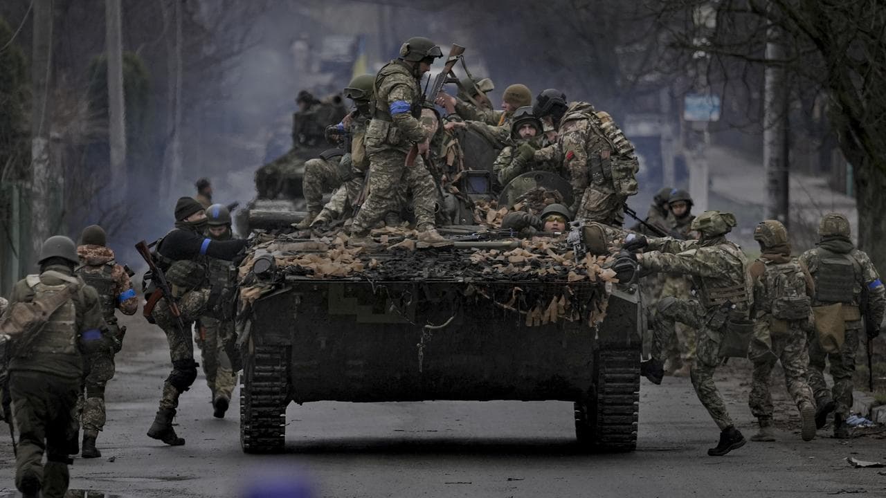 Ukrainian servicemen climb on a vehicle outside Kyiv