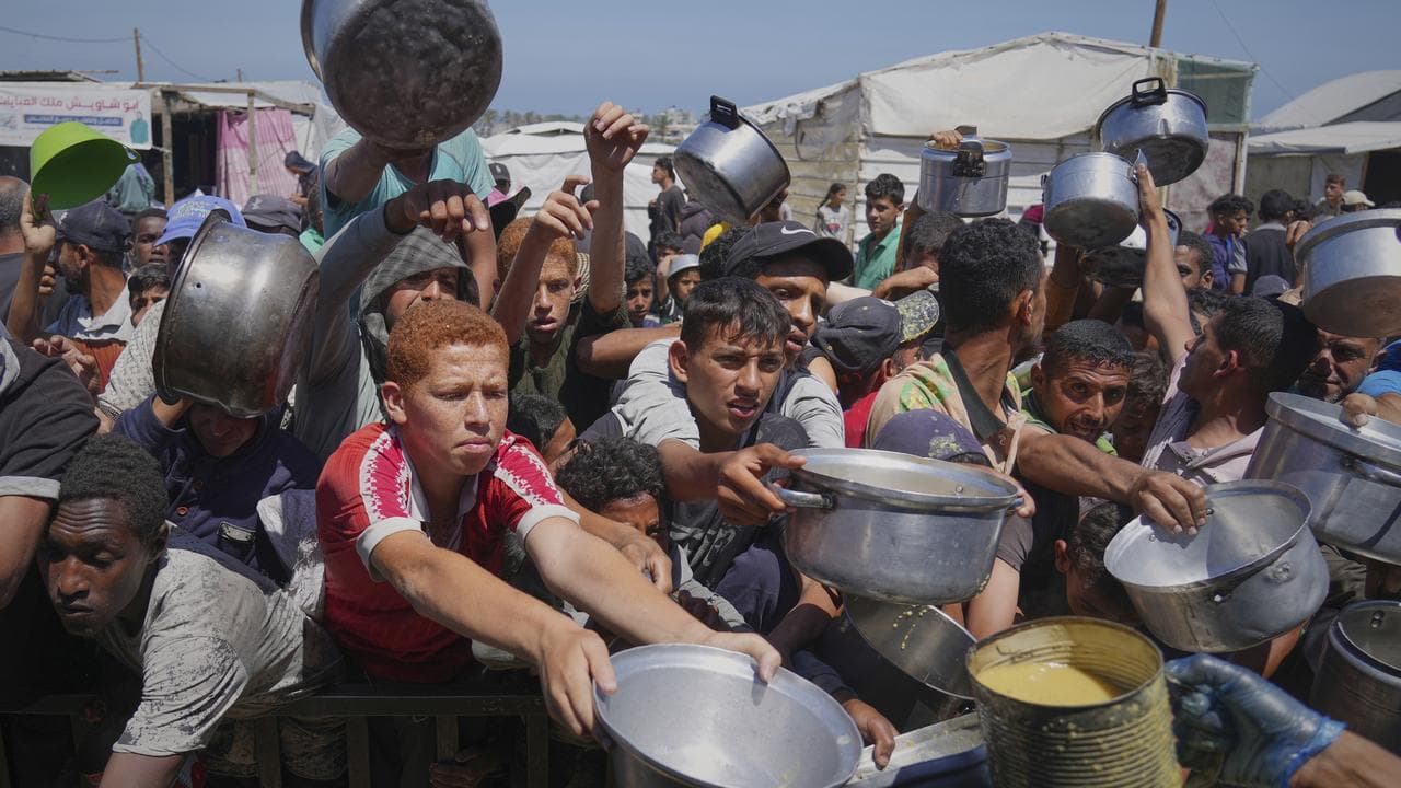Palestinians struggle to receive cooked food from a community kitchen