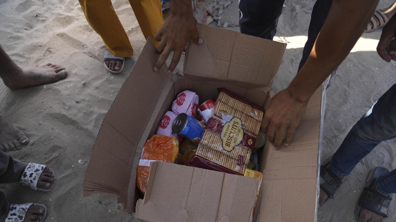 Palestinians open a box containing food and humanitarian aid