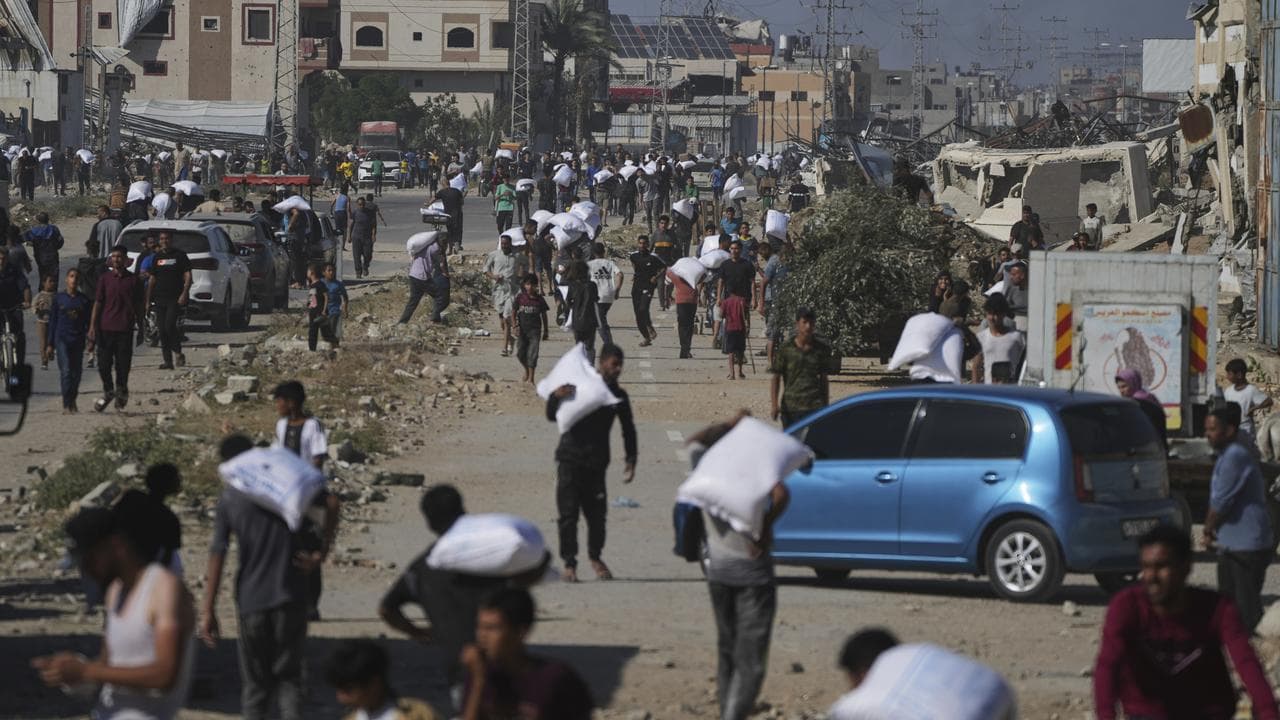 Palestinians carry bags of food aid