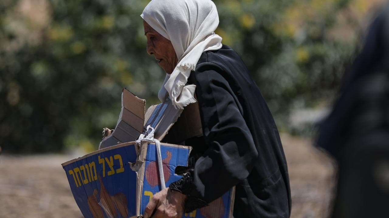 A Palestinian woman carries aid supplies