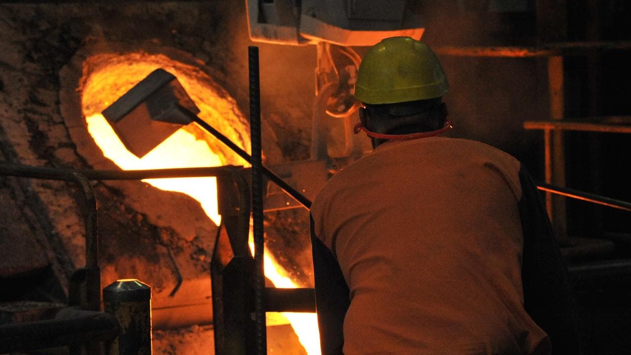 A factory worker prepares molten iron for pouring