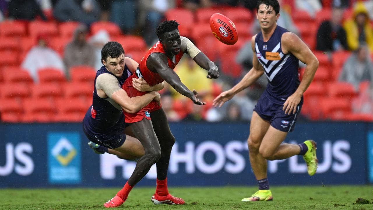 Mac Andrew handballs despite attention from Fremantle's Jordan Clark.