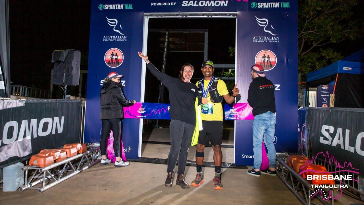 Harold Matthews stands with woman at a trail run finish line.