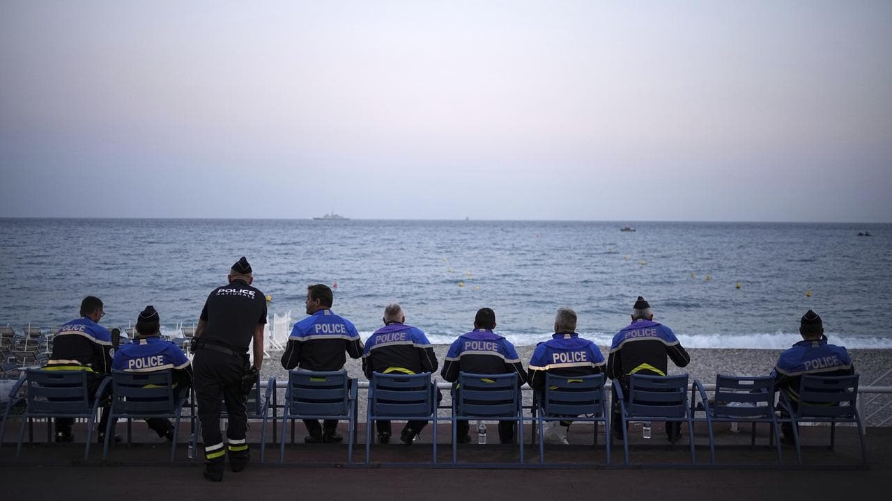 Police officers sit in front of the Mediterranean Sea