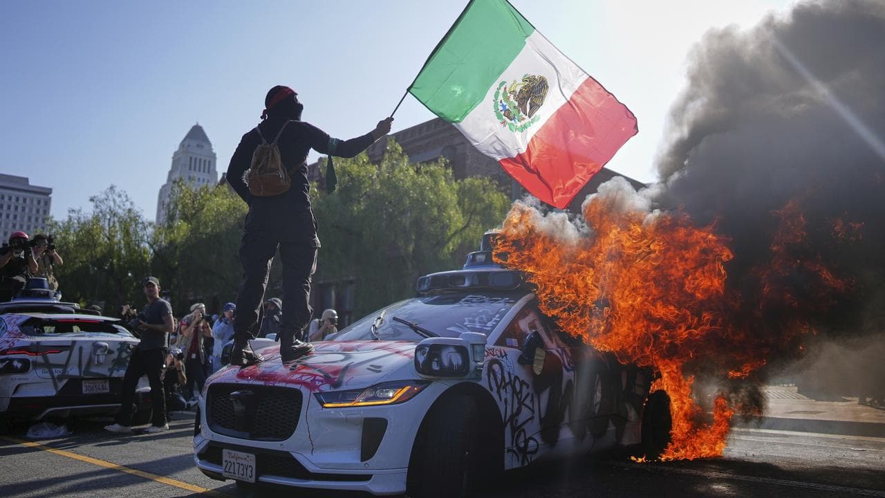 Protesters stands on a burning car in downtown Los Angeles