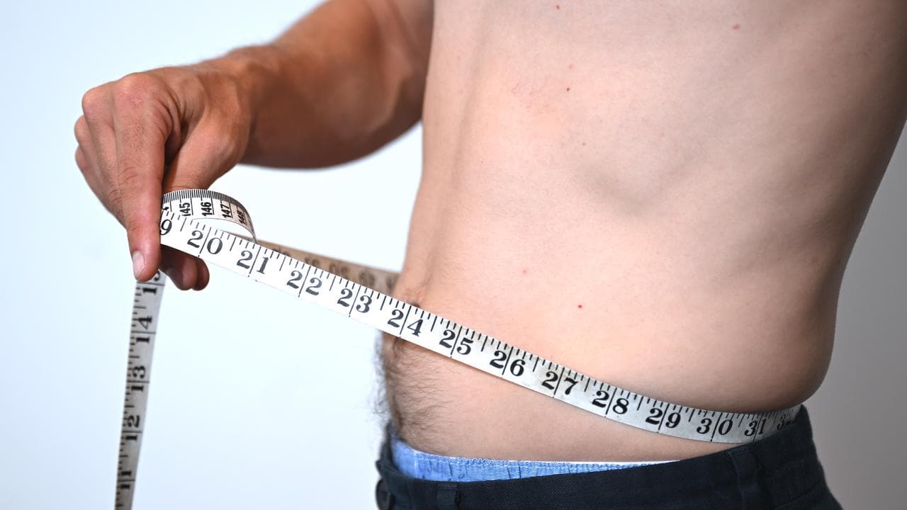 A man uses a measuring tape around his hip