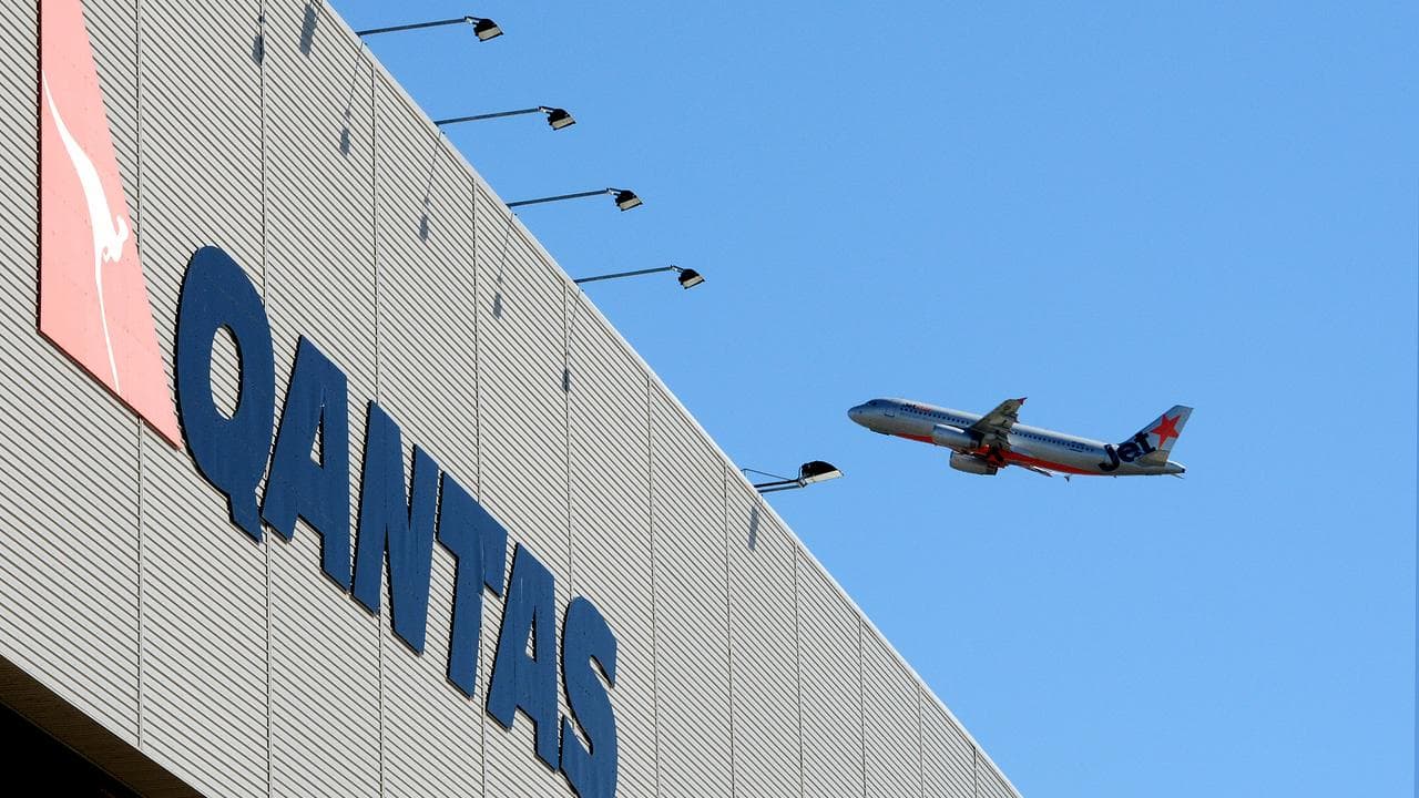 A Jetstar plane flies above Qantas signage (file image)