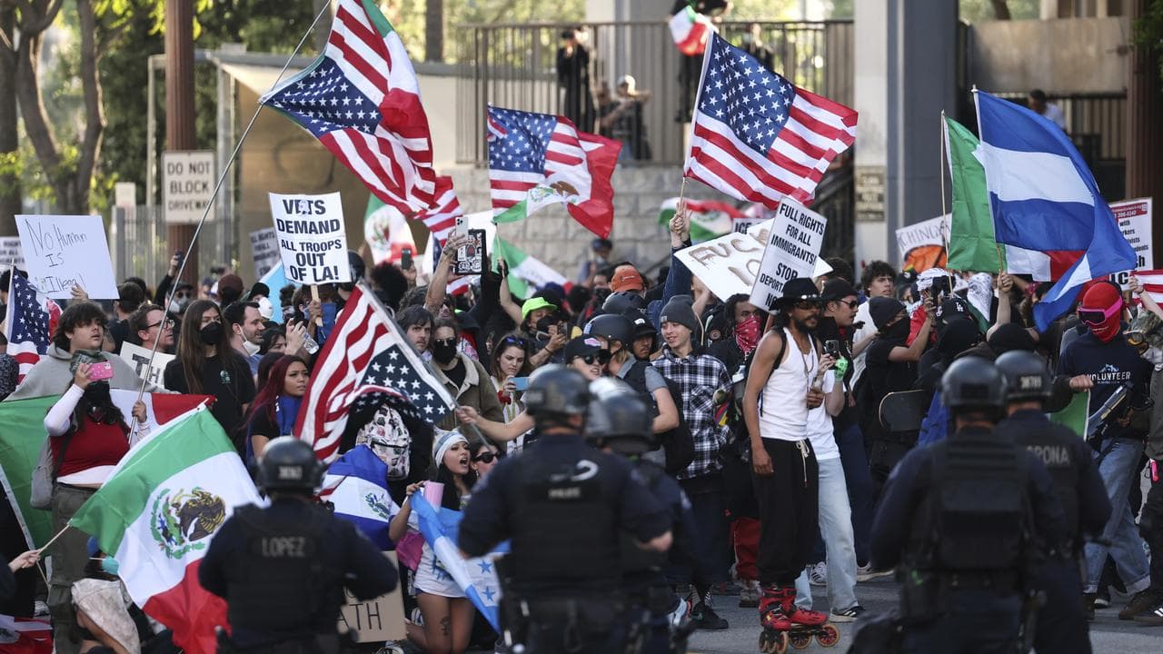 Law enforcement officers stand guard as demonstrators protest in LA