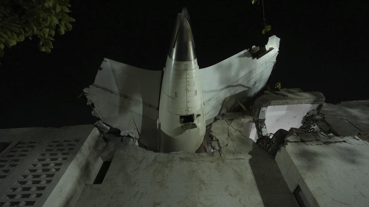 Tail of crashed airplane stuck in a building at a crash site in India