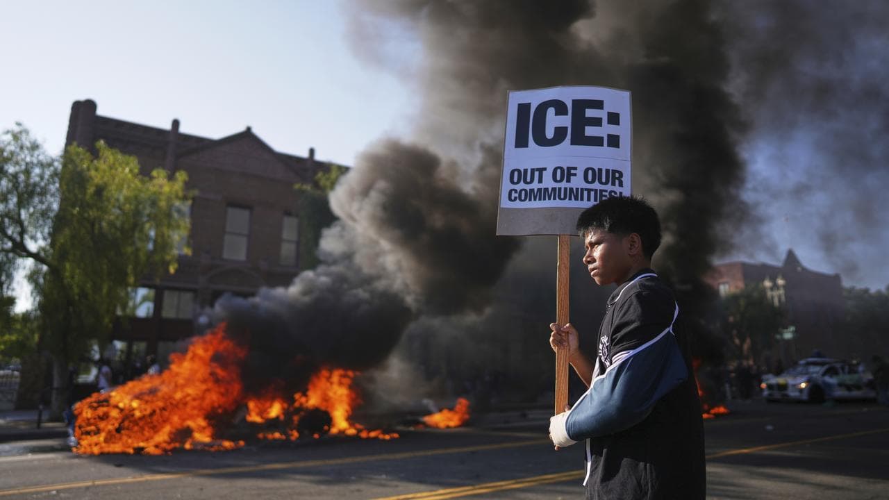 Protester as a Waymo taxi burns in downtown Los Angeles