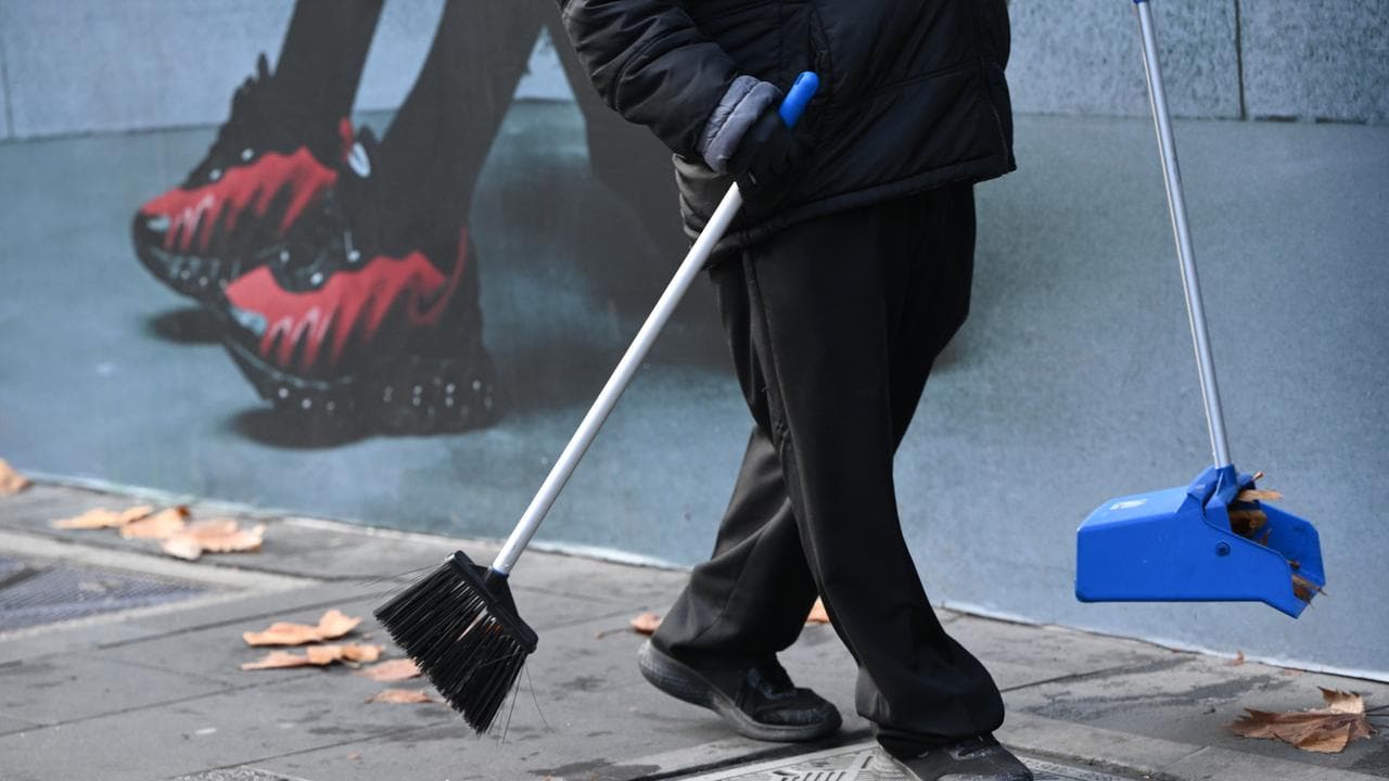 A cleaning worker sweeps leaves 