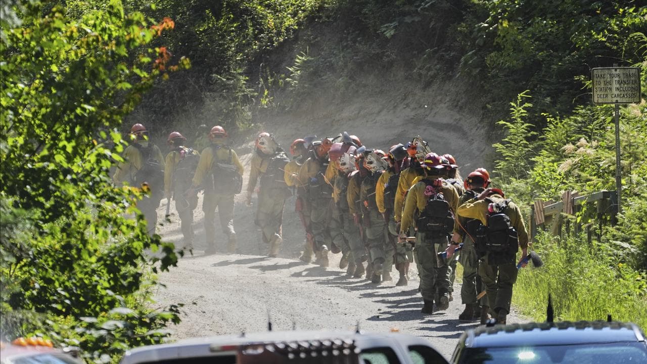 A line of wildland firefighters arrive at the scene of the wildfire
