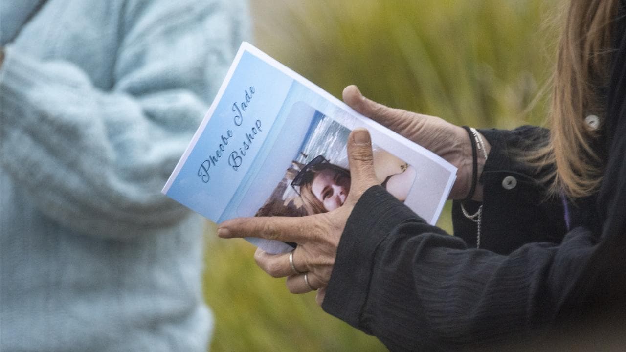 A mourner holds an order of service during a funeral for Pheobe Bishop