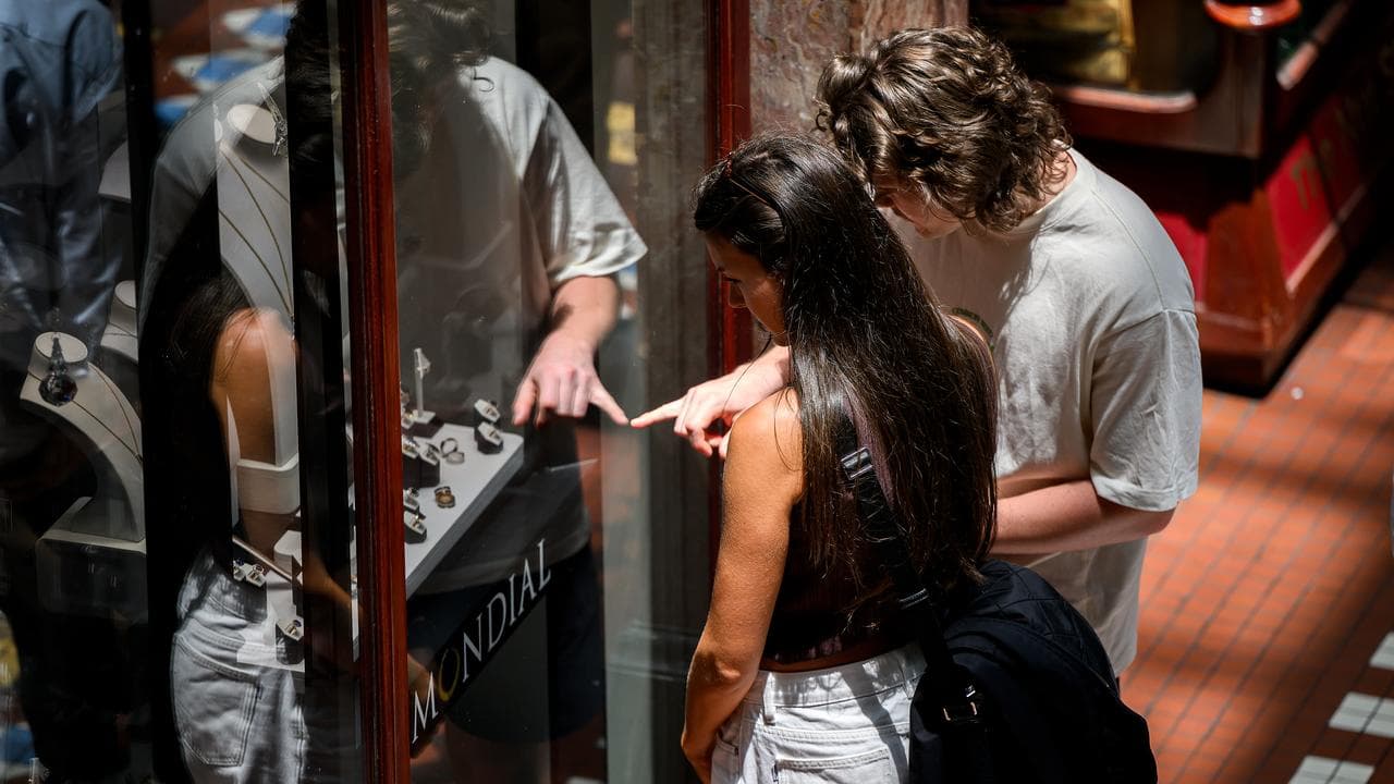 Man and woman look at rings in window