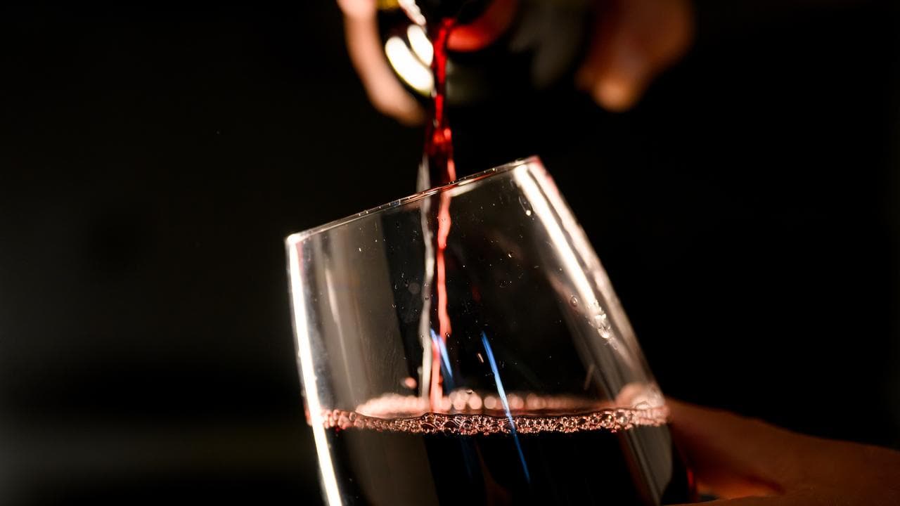 Glass of red wine is poured