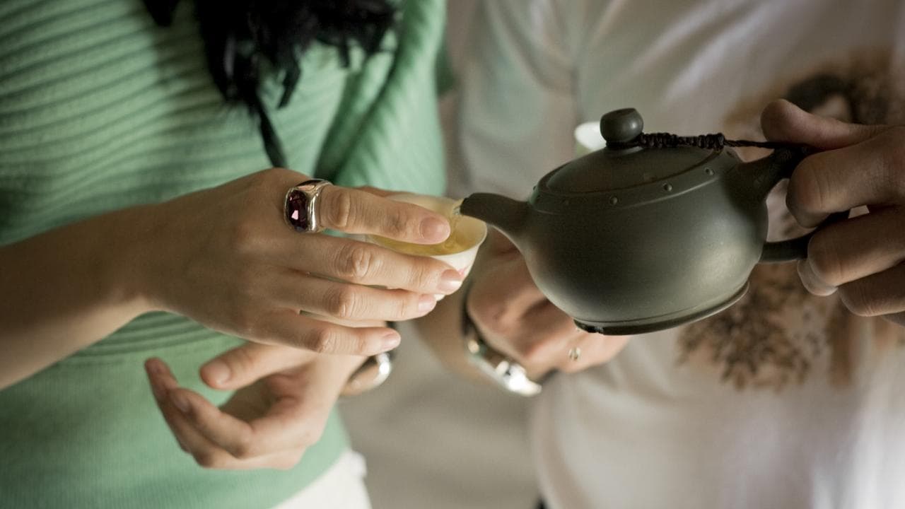 Tea is poured from a teapot into a small cup