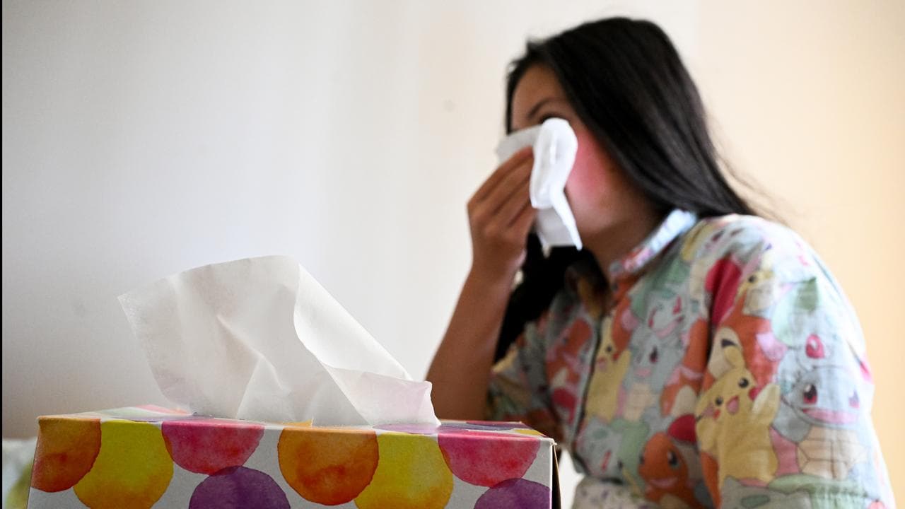 A young woman with flu uses tissues, Canberra, July 2023