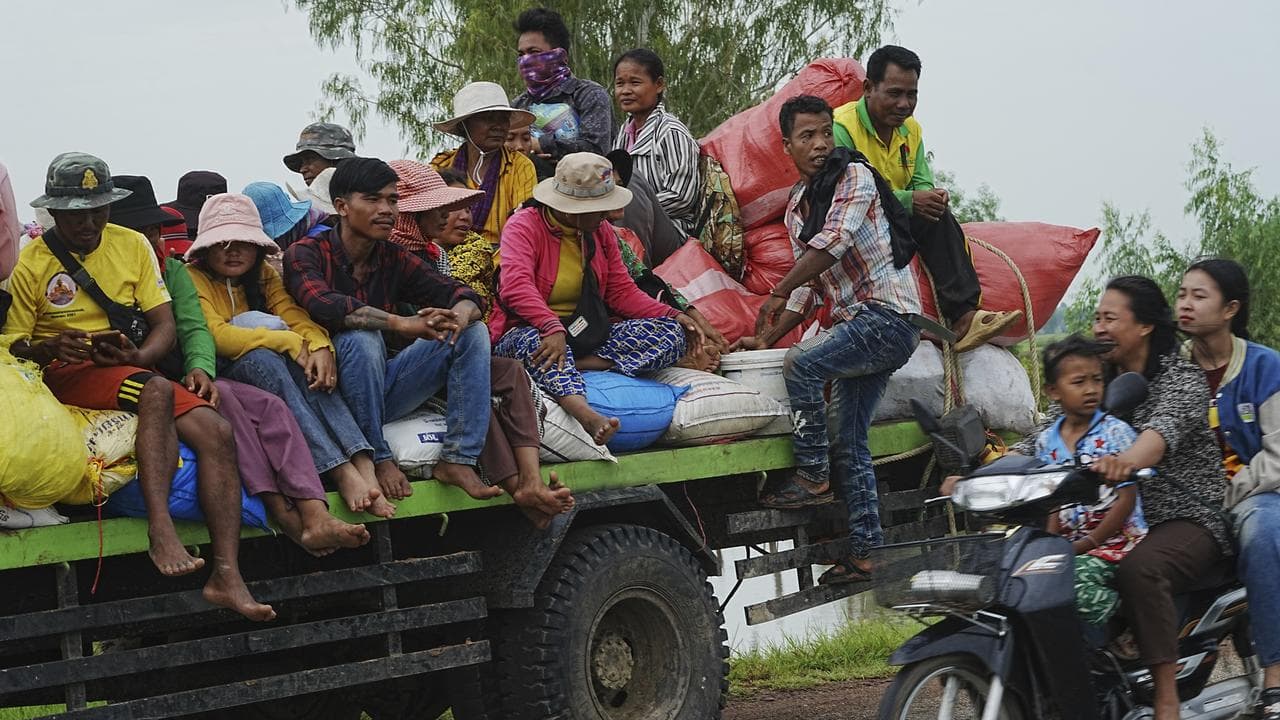 Cambodians sit on a cart of a tractor
