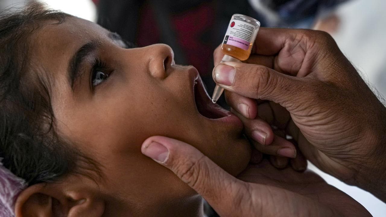 A health worker administers a polio vaccine to a child.