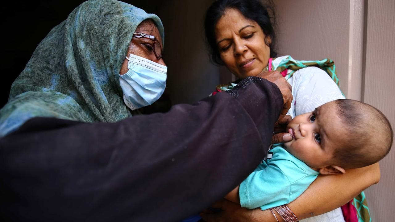 A health worker administers polio vaccine to children.