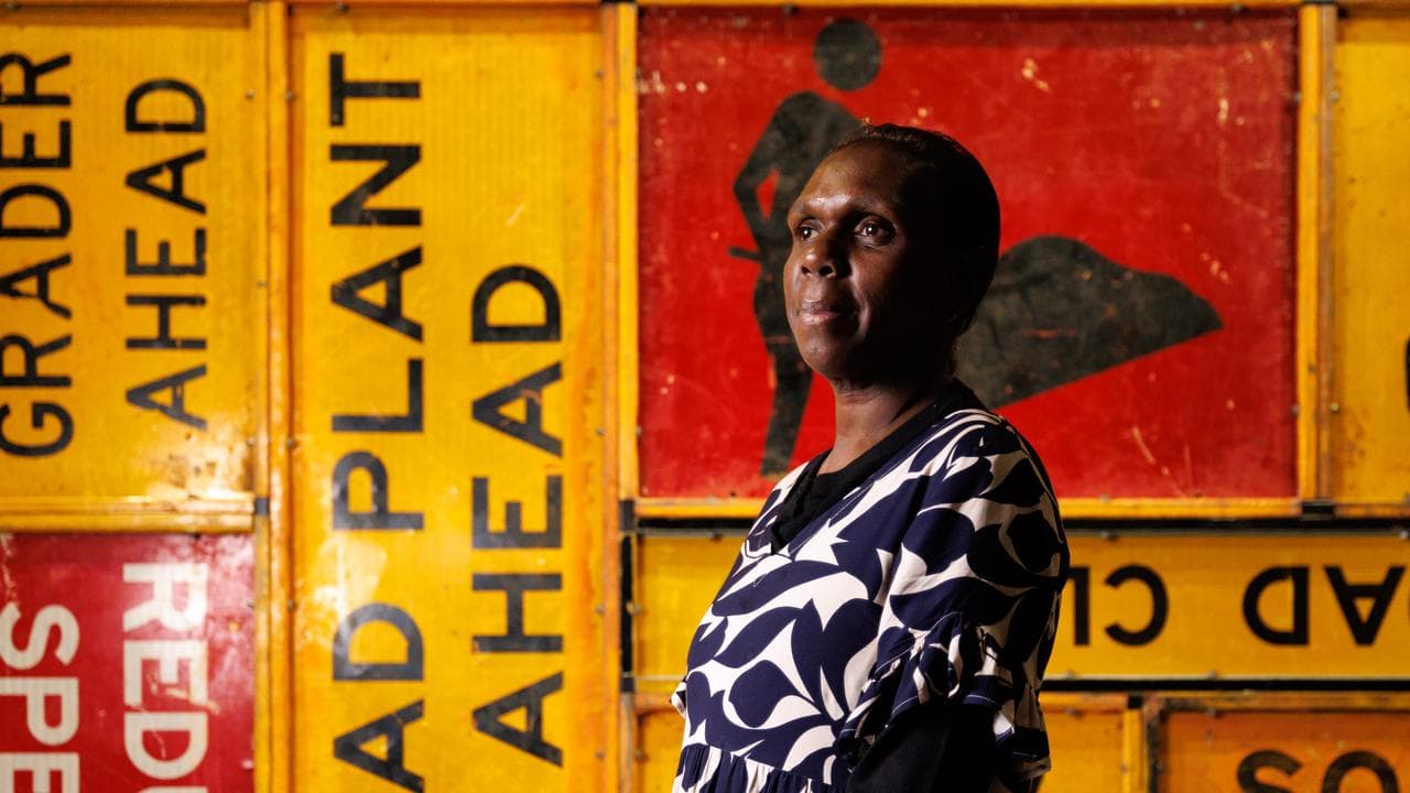 yolgu arlist Gaypalani Wanambi in front of her etched metal arkwork