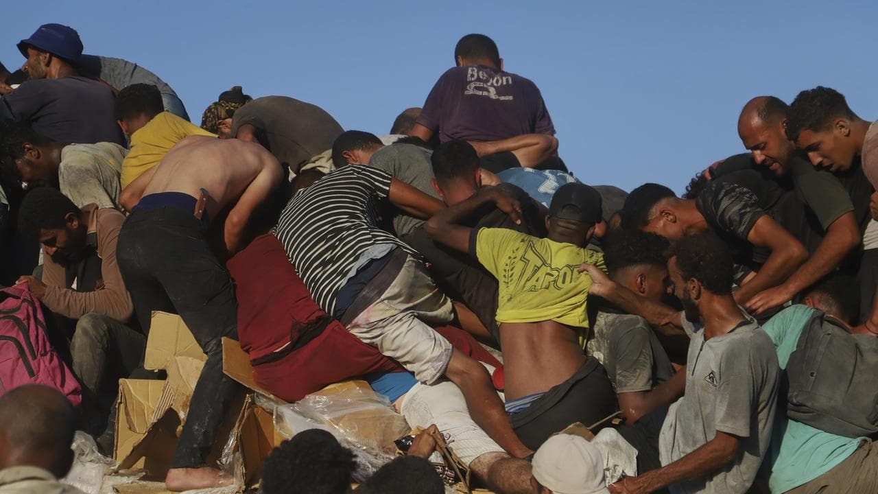 Palestinians ride on a truck loaded with food and aid