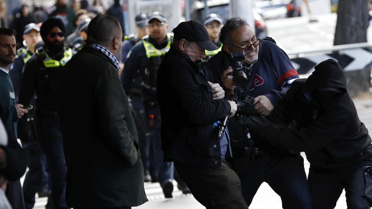A protester attacks members of the press