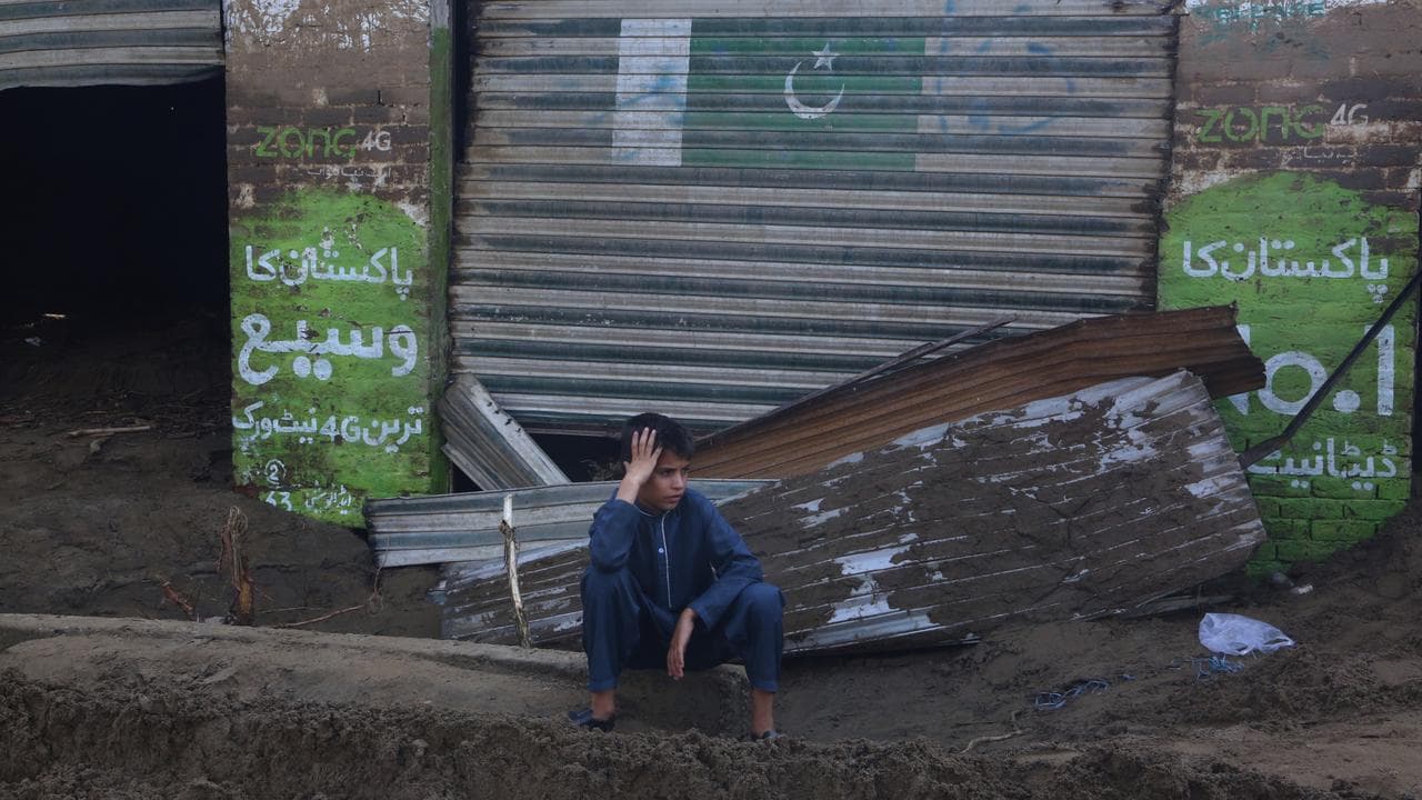 A boy in front of shops damaged by flash flooding in Buner district