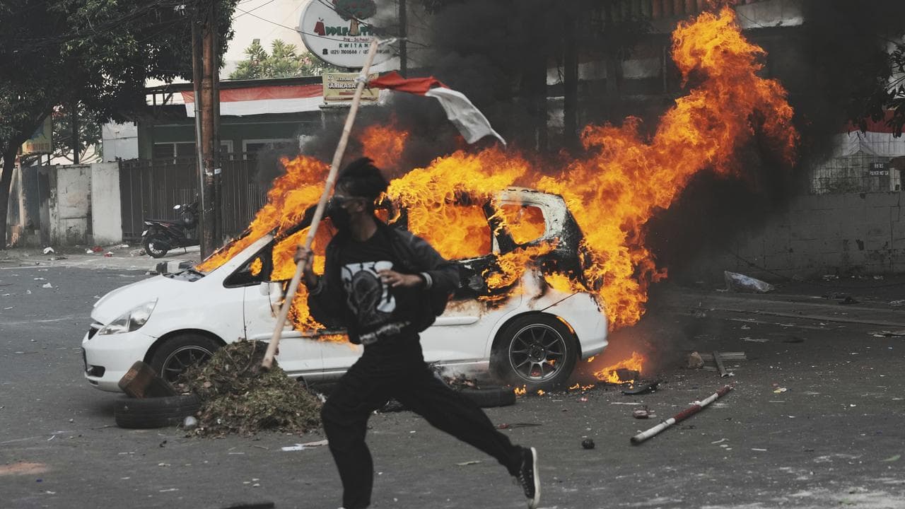 Protester runs past burning car in Jakarta