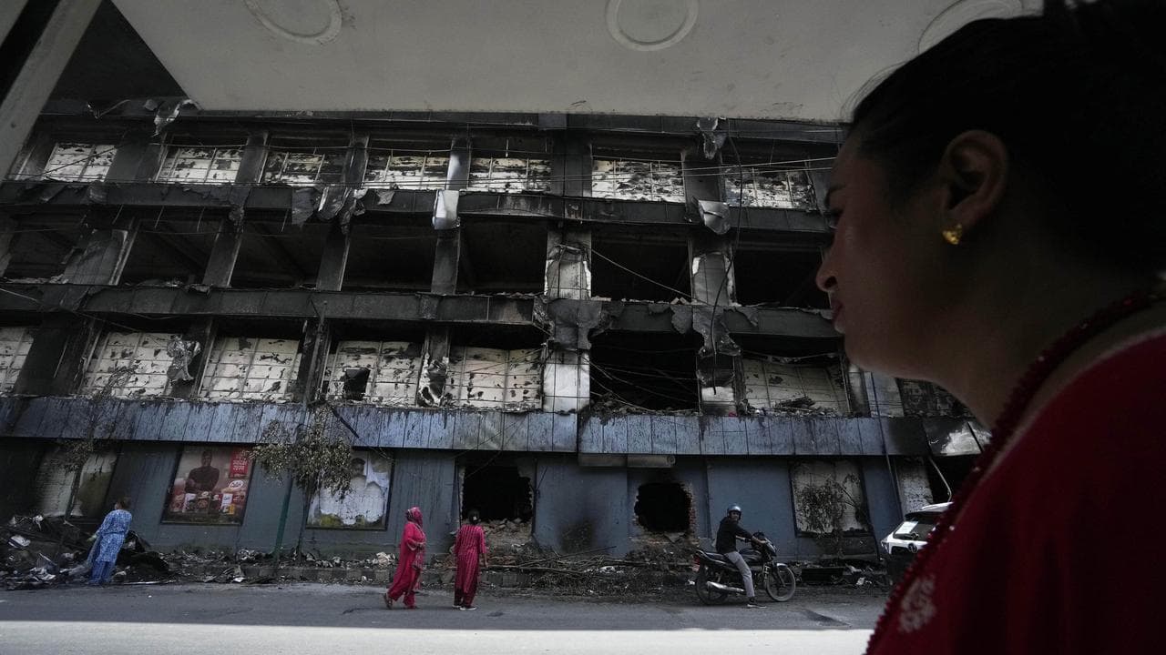 Nepalese people inspect a building