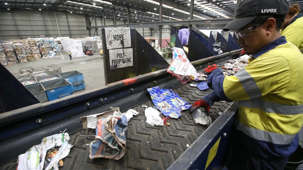 Workers manually sort waste from domestic recyclables (file)