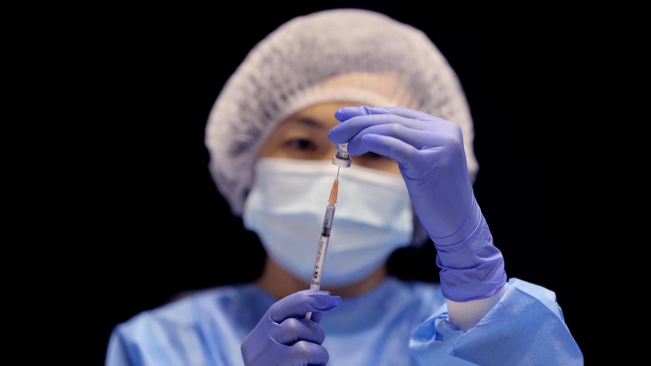 A health care worker fills a syringe
