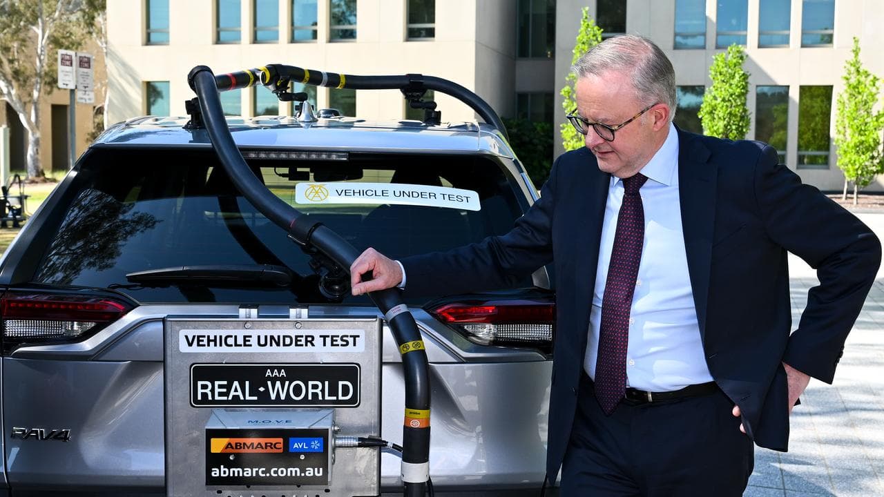 A photo of Anthony Albanese with a car undergoing an emissions test.