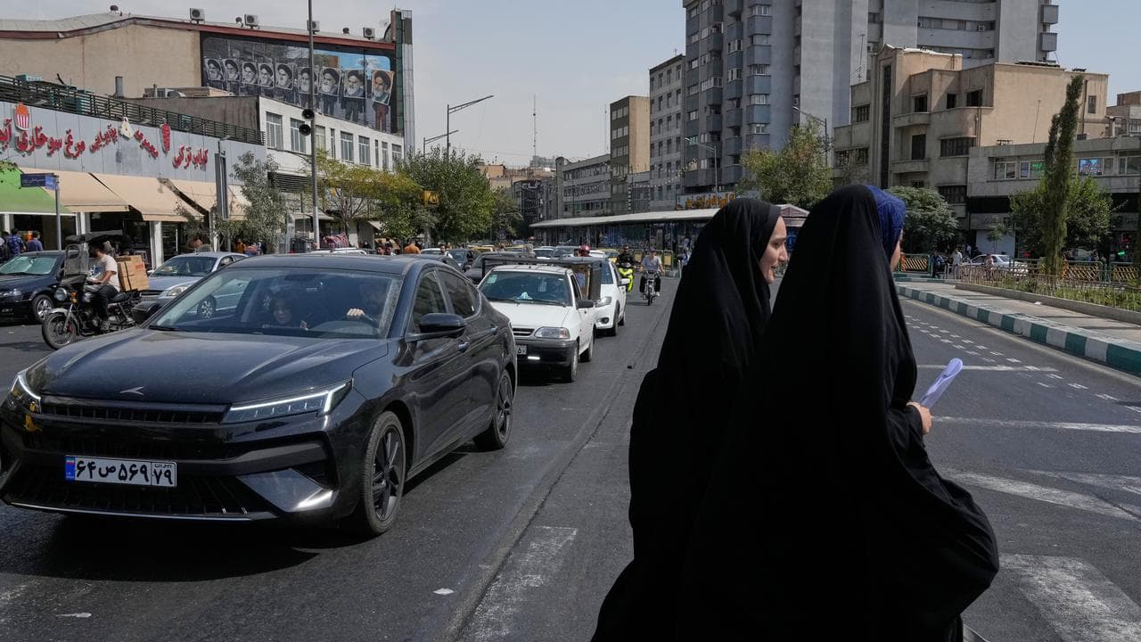 Women cross the Islamic Revolution square, in Tehran