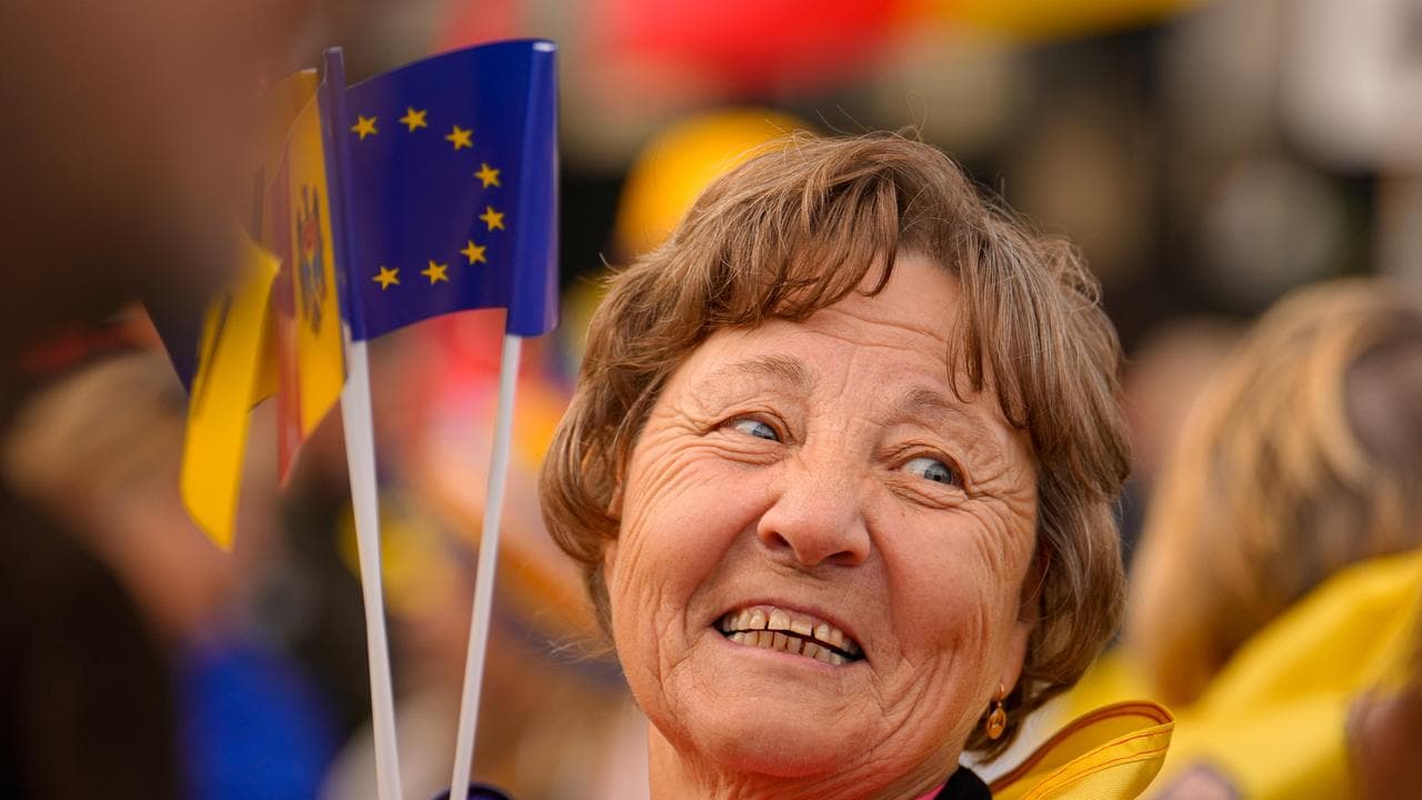 A woman smiles as she holds Moldovan and EU flags