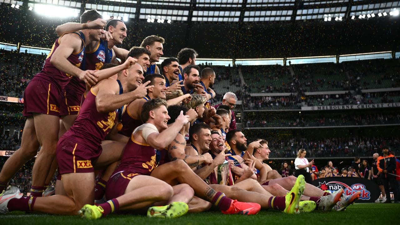 Brisbane Lions players celebrate with the premiership cup