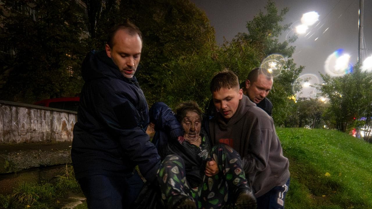Neighbours carry an injured woman after a Russian strike in Kyiv